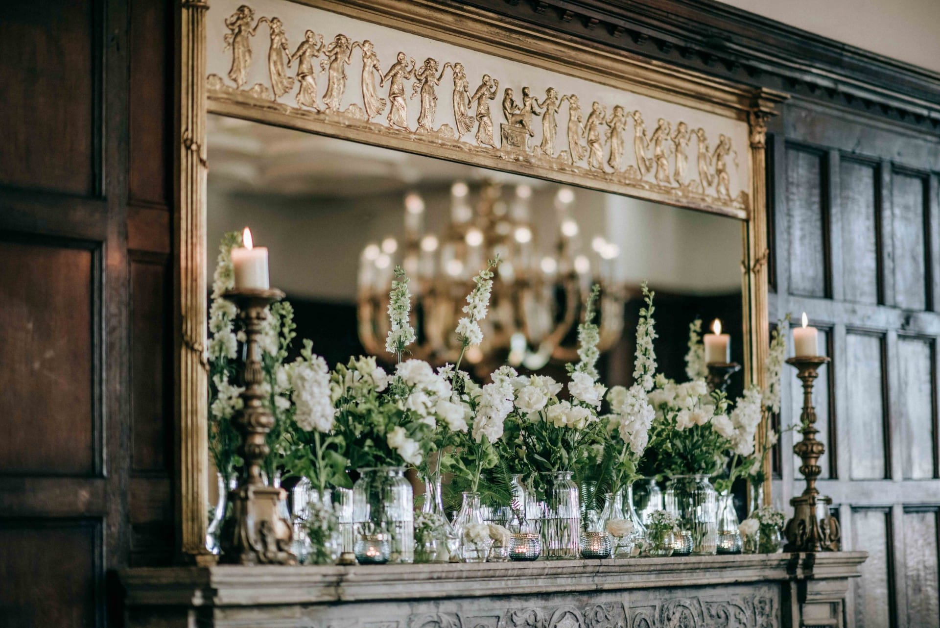 Flower display above a fireplace set against a mirror